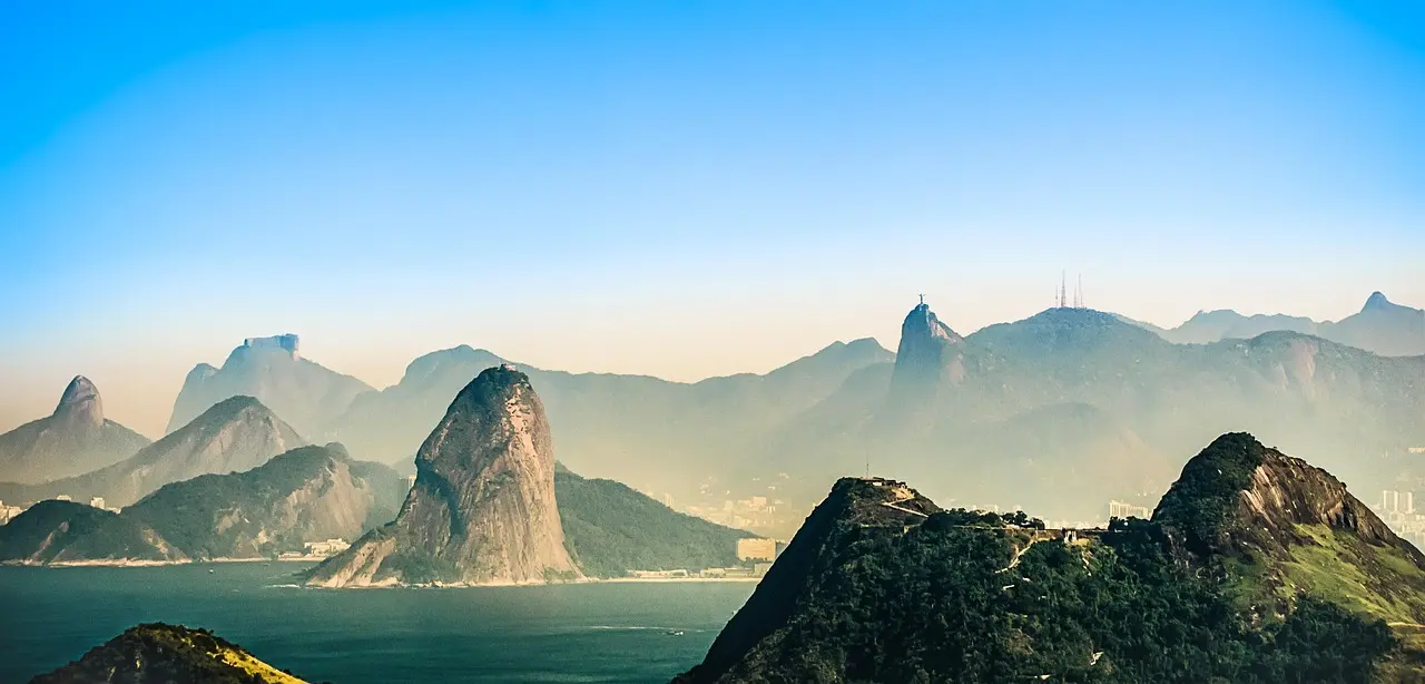 Aerial view of Christ the Redeemer statue overlooking Rio de Janeiro's coastline and lush mountains