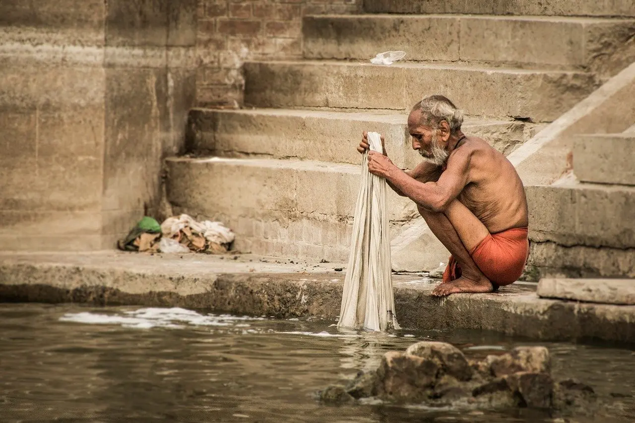 At dawn in Varanasi, pilgrims immerse themselves in the sacred waters of the Ganges — a core rite of Hindu religious pilgrimage believed to purify karma and awaken spiritual awareness. Sunrise over the Ganges River in Varanasi with pilgrims performing ritual bathing at the stone ghats