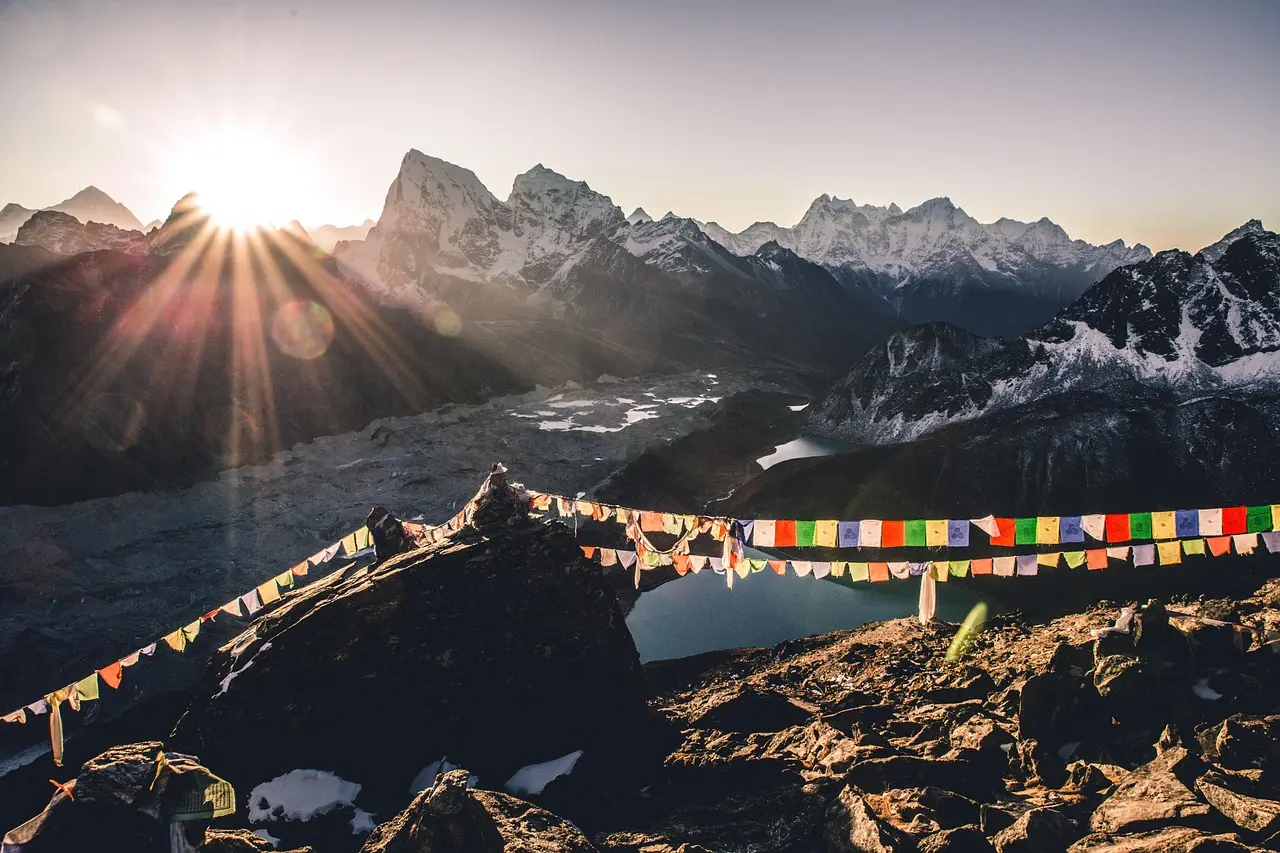 Sunrise over the Himalayas — a transcendent moment to appreciate natural scenery in Nepal's Khumbu region Panoramic view of snow-covered Himalayan peaks at sunrise, with prayer flags strung across a rocky ridge