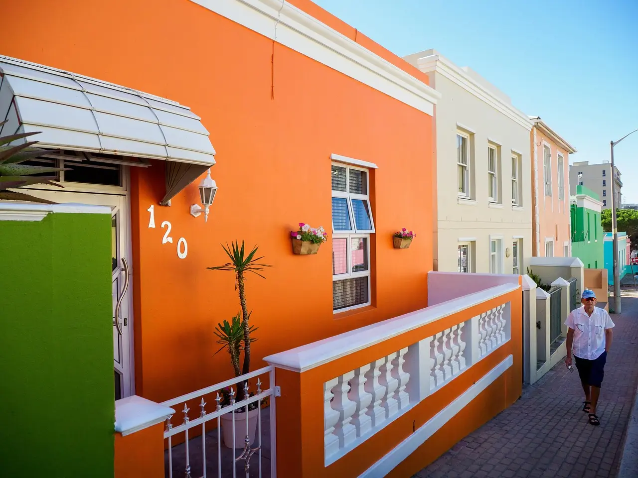 A vivid street-level view of Bo-Kaap’s iconic pastel homes — a joyful, culturally rich landmark that adds essential diversity to any global list of travel destinations for landmark photography Bo-Kaap neighborhood in Cape Town with brightly painted houses, minaret, and cobblestone street