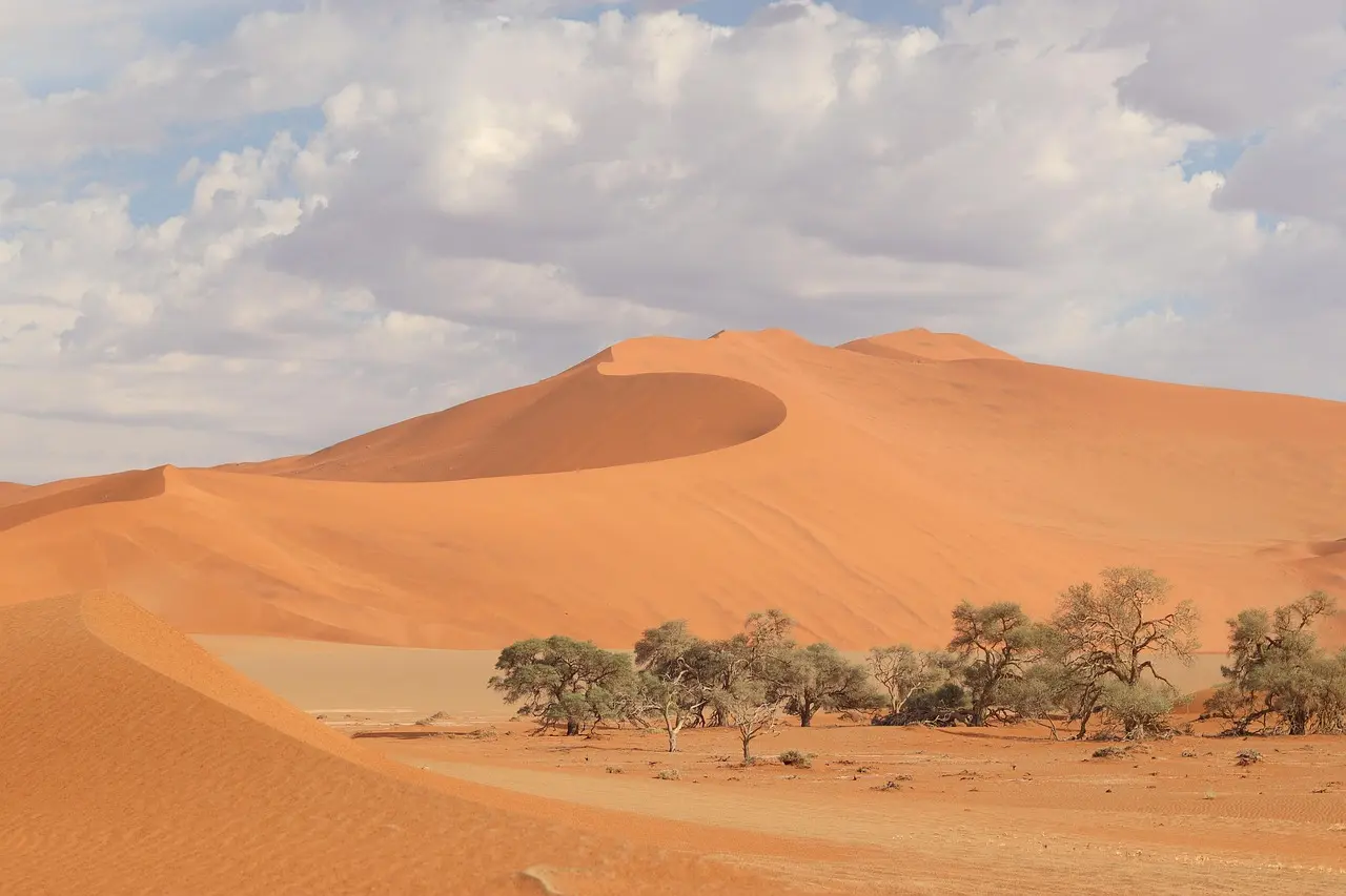 A solitary ascent at dawn — a meditative ritual to appreciate natural scenery in Namibia’s ancient desert Silhouette of a lone traveler climbing the crest of a tall red sand dune at sunrise in Sossusvlei