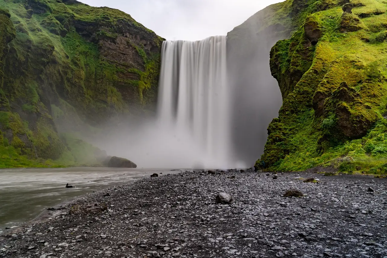 A bird’s-eye view of geological artistry — how Iceland’s terrain invites intimate appreciation of natural scenery Overhead drone shot of winding Fjaðrárgljúfur Canyon with green moss-covered basalt walls and a narrow river snaking below