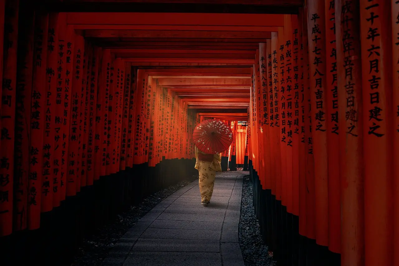 A weathered wooden torii gate marks the entrance to Ise Grand Shrine in Japan — the heart of Shinto religious pilgrimage and a living expression of reverence for nature and cyclical renewal. Traditional wooden torii gate leading to Ise Grand Shrine through mossy forest path in spring