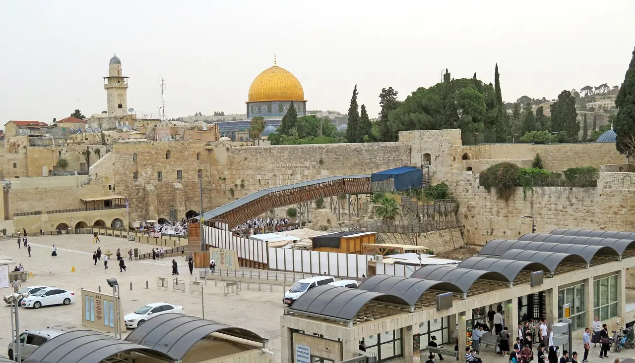Devotees gather at the Western Wall in Jerusalem at golden hour — a focal point of Jewish religious pilgrimage and a symbol of enduring faith across generations. Crowded Western Wall plaza with worshippers placing prayers in stone crevices at sunset