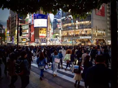 Aerial view of Tokyo's Shibuya Crossing at dusk, filled with pedestrians and neon signs