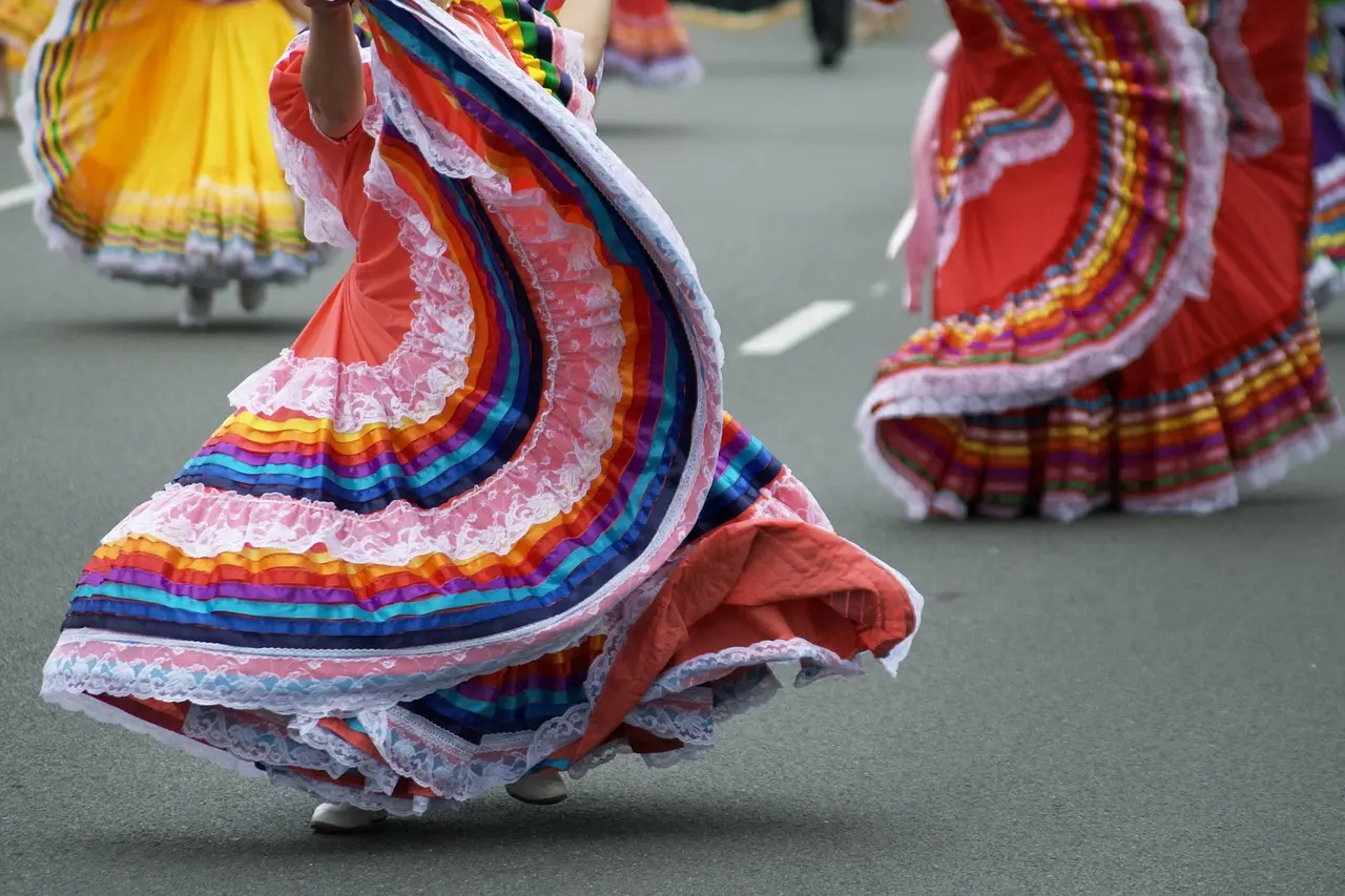 A vibrant group of dancers in traditional Oaxacan costumes performing outdoors during daylight