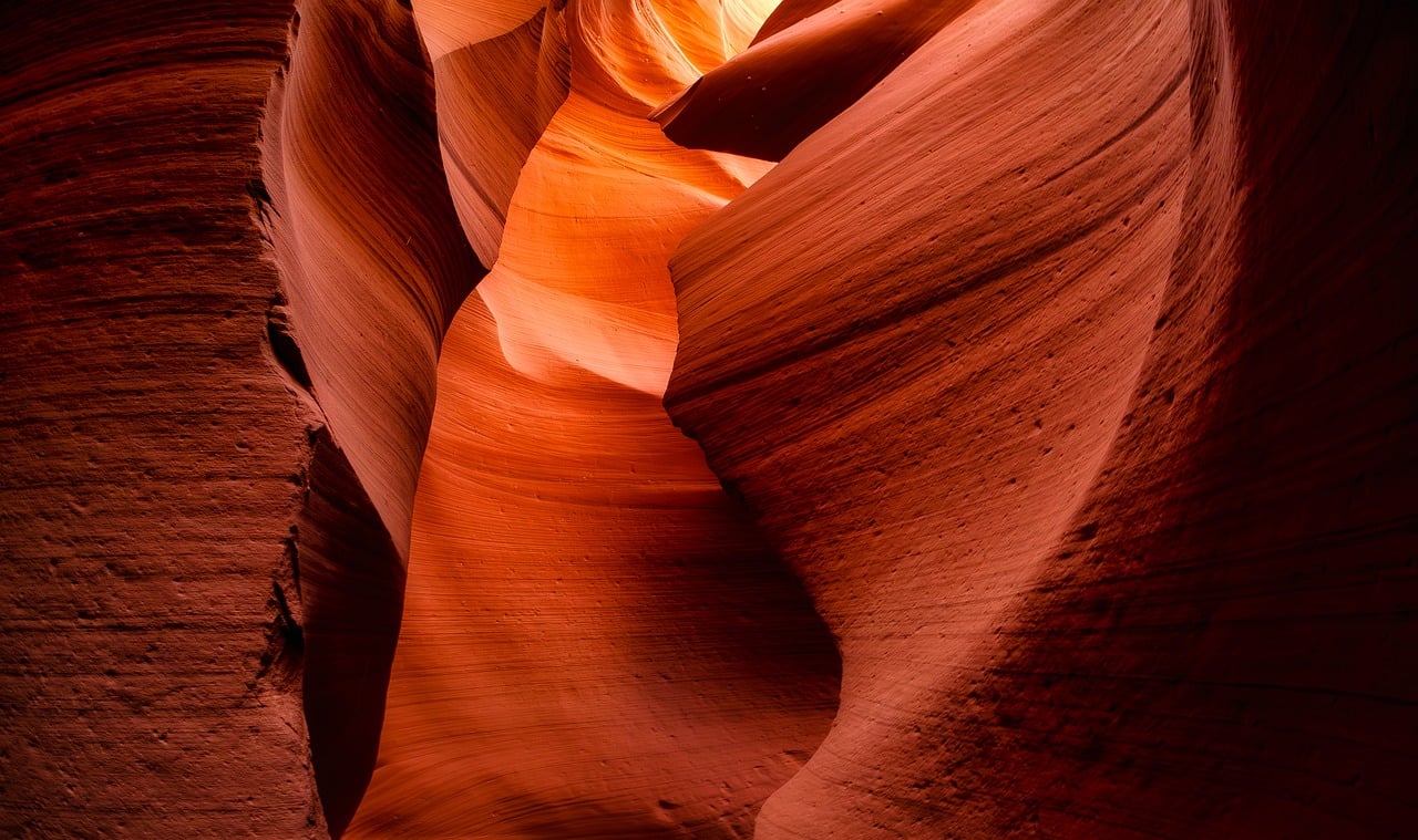 Sunlight streaming through the narrow opening of Antelope Canyon, illuminating curved sandstone walls