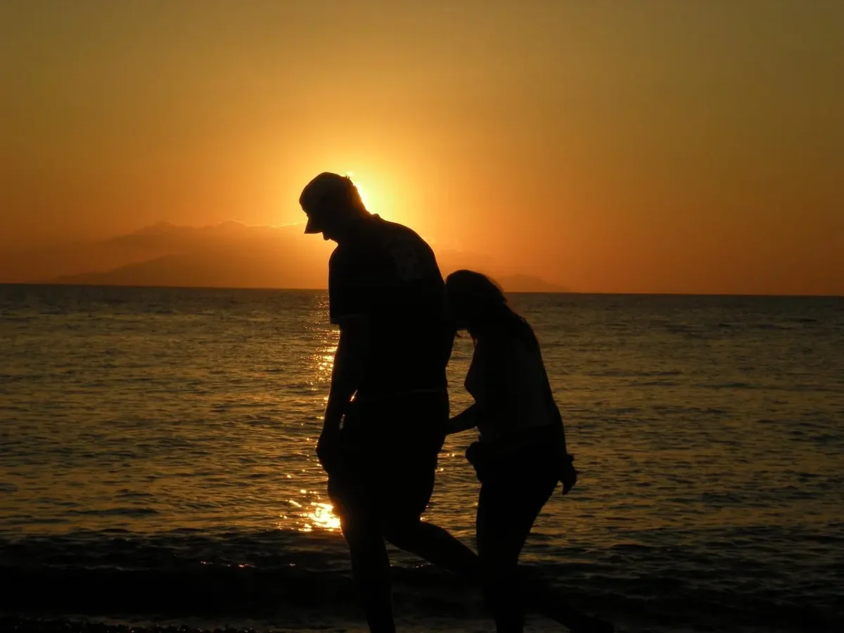 Aerial view of Santorini's white-washed buildings cascading down volcanic cliffs toward the Aegean Sea at golden hour